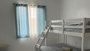 A bunk bed room with a window, curtains, a small table, and a trash bin. - Peaceful Stay at Yena’s Inn (Cauayan)