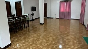 A spacious room with a wooden floor, a dining area with chairs and a table, a television, and an air conditioning unit. - Relax in Comfort at Yena’s Inn (Cauayan)