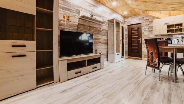 Una cocina moderna con armarios de madera, televisión integrada y un comedor con sillas.