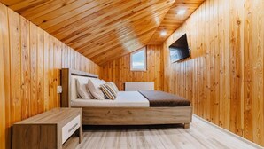 Una habitación con paneles de madera, una cama, una mesita de noche y una ventana.