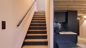 A modern staircase leading to a kitchen area with a built-in refrigerator.