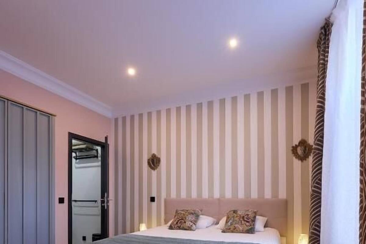 Una camera da letto con un letto, un armadio, uno specchio e una parete a righe.