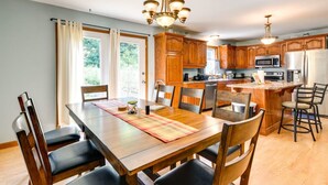 A kitchen with wooden cabinets, a dining table with chairs, and a central island with bar stools.