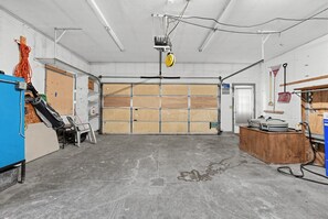 Eine Garage mit Betonboden, einer Holztür und verschiedenen Werkzeugen und Geräten.