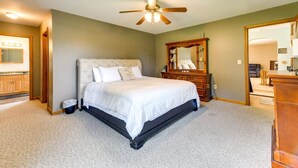 A bedroom with a bed, a dresser, a mirror, and a ceiling fan.