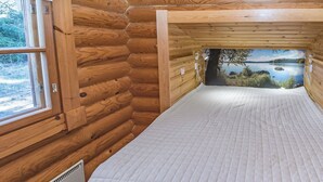 Un dormitorio tipo cabaña de madera con una cama, una ventana y vista a un lago.