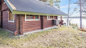 Una cabaña de madera con techo inclinado, un pequeño porche y vistas a un lago.