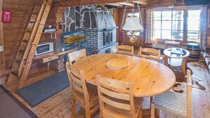 Un interior de madera con chimenea de piedra, mesa y sillas de madera.