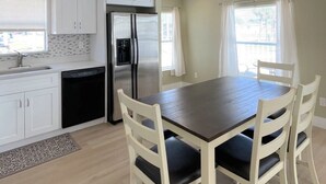 A modern kitchen with white cabinets, a stainless steel refrigerator, and a dining table with four chairs. - BETTER THAN NEW - FULLY REMODELED - SHORT-TERM RENTAL FRIENDLY (Fort Myers)