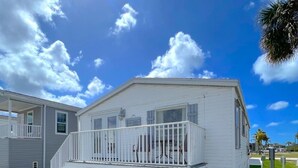 A white mobile home with a balcony, a garage, and a small porch. - BETTER THAN NEW - FULLY REMODELED - SHORT-TERM RENTAL FRIENDLY (Fort Myers)