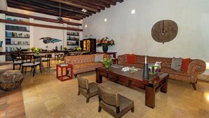 A spacious living area with a high ceiling, a bar area with bookshelves, and a patterned sofa. - Luxury Old City with Pool and Jacuzzi, 8 Bedrooms (Cartagena de Indias)
