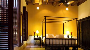 A four-poster bed with a nightstand and lamp, a wooden bench, and a large mirror. - Luxury Old City with Pool and Jacuzzi, 8 Bedrooms (Cartagena de Indias)