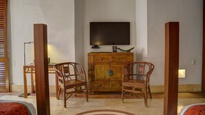 A room with a television mounted on the wall, a wooden cabinet, two wicker chairs, and a small table. - Luxury Old City with Pool and Jacuzzi, 8 Bedrooms (Cartagena de Indias)