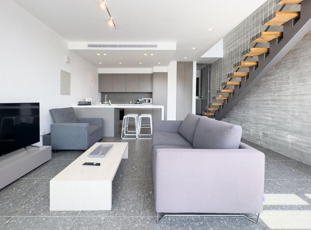 Un salon moderne comprenant un canapé, une table basse, un téléviseur et un escalier menant à un niveau supérieur.