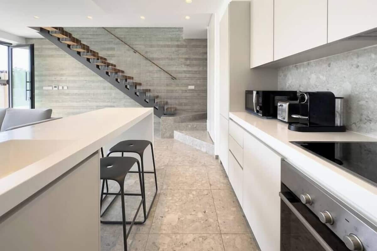 A modern kitchen with a central island, bar stools, a microwave, toaster, and a built-in oven.