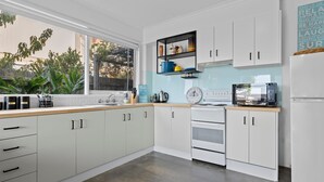 Eine moderne Küche mit weißen Schränken, einer Edelstahl-Spüle und einem eingebauten Backofen.
