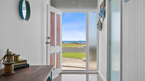 An open door leading to a view of the ocean, a wooden table with books, and a mirror on the wall. - Esplanade Escape - Beautiful Esplanade Escape in Indented Heads (Indented Head)