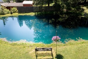 Une piscine extĂ©rieure aux eaux claires, entourĂ©e dâune clĂŽture en bois, avec un banc et un pot de fleurs.