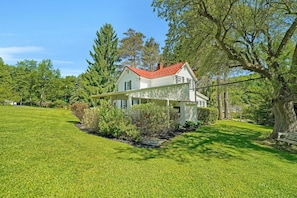 A house with a red roof, surrounded by a well-maintained lawn and trees. - Five Pines Lodge ATV & Snowmobile Friendly (Coudersport)
