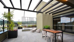 A modern outdoor terrace with a dining area, seating, and potted plants. - Studio em frente a UFSC e HU - 709A (Florianópolis)