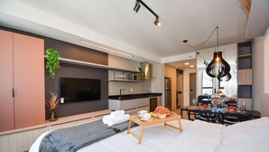 A modern hotel room with a bed, bedside table, and a dining area with a table set for two. - Studio em frente a UFSC e HU - 709A (Florianópolis)