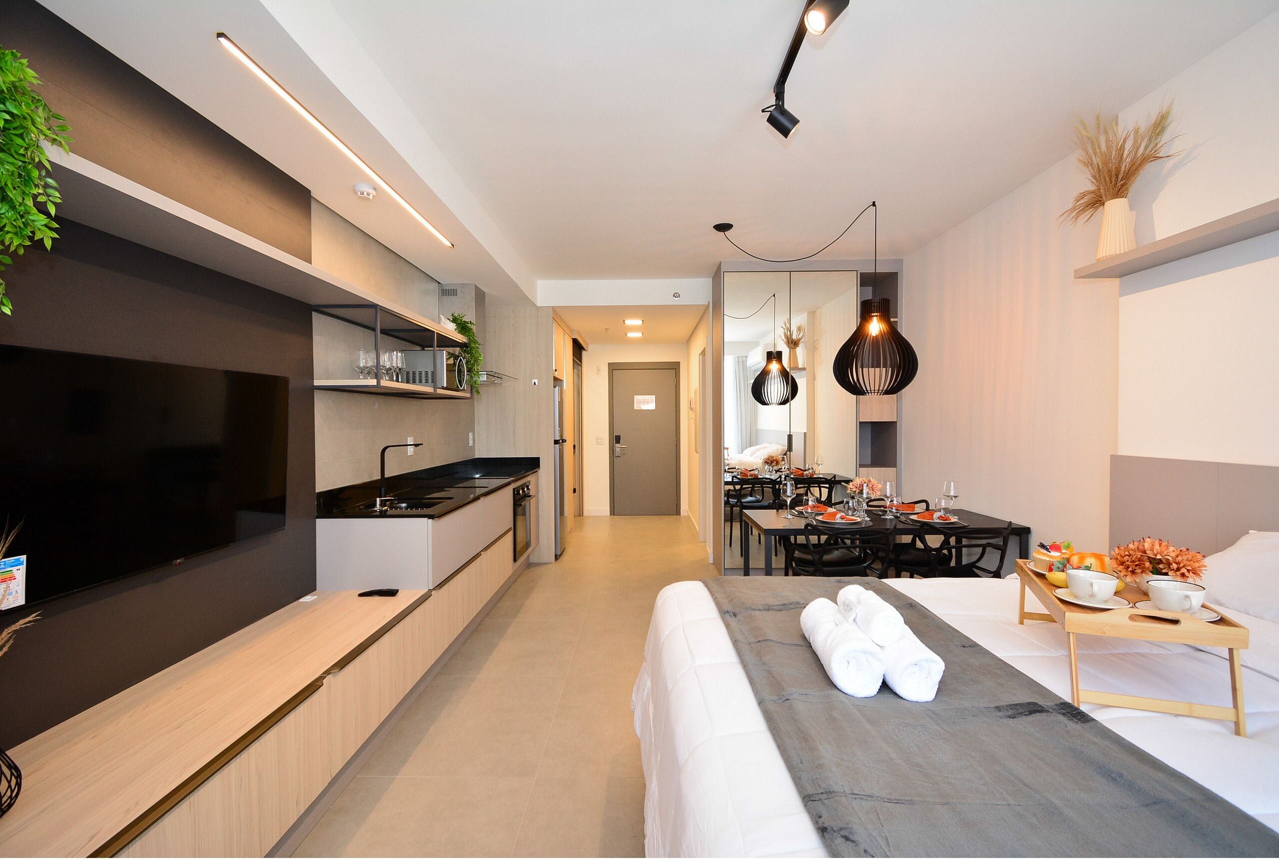 Une chambre d’hôtel moderne dotée d’un grand lit, d’un coin repas, d’une cuisine et d’une télévision.