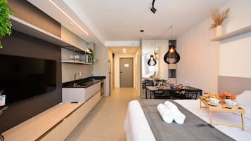 Une chambre d’hôtel moderne dotée d’un grand lit, d’un coin repas, d’une cuisine et d’une télévision.