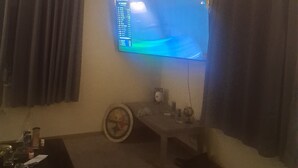 Ein Wohnzimmer mit Deckenventilator, einem Wand-Flachbildfernseher, einem Couchtisch und einem kleinen Beistelltisch mit Globus und weiteren Gegenständen.