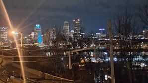 Eine beleuchtete Stadtlandschaft bei Nacht mit Gebäuden und einer Brücke.