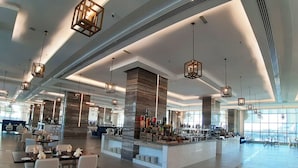 Un amplio hall de hotel con mobiliario moderno, una zona de bar central y ventanas grandes que aportan luz natural.