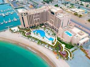 Un hotel grande con una piscina central, una zona de playa y un puerto deportivo.