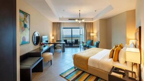 A hotel room with a bed, desk, chair, and a view of the outdoors. - Peaceful Getaway in a Room Overlooking the Enchanting Indian Ocean (Fujairah)