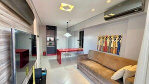 Ein modernes Wohnzimmer mit einer Couch, einem Essbereich mit einem roten Tisch und einer Wand mit abstrakter Kunst.