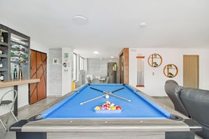 A pool table with balls and cues, a seating area with a sofa, a dining table, and a bar area with bottles. -  5-bedroom Combo apartment in lleras Medellín with AC (Medellín)