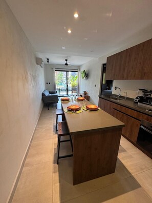 A modern kitchen with a central island, wooden cabinets, and a dining area with a sofa and chairs. - The heart of Santa Cruz steps from the beach! (Crucecita)
