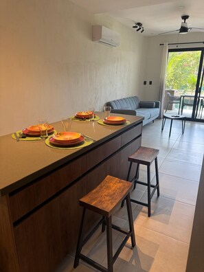 Una cucina moderna con isola centrale, sgabelli da bar e zona pranzo con divano e sedie.