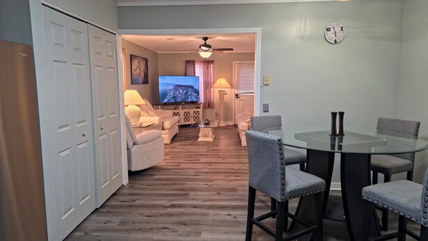 A living room with a television, sofa, and dining area with chairs and a table.
