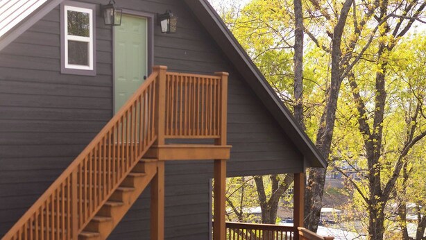 Una cabaña con terraza de madera, escaleras y una puerta.