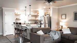 A modern kitchen with a central island, bar stools, a sofa, and a dining table. - Cozy Lake Escape: Unwind with Stunning Lake Views in New Eucha. (Eucha)