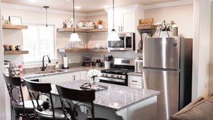 Una cocina moderna con una isla central, electrodomésticos de acero inoxidable e iluminación colgante.