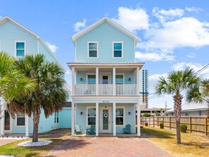 A two-story house with a balcony, a porch with chairs, and a number '5113' on the front. - Rooftop Deck, Game Room, Fire Pit, Sleeps 16 (Panama City Beach)