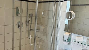 Un baño moderno con ducha de vidrio, un lavamanos blanco y un espejo.