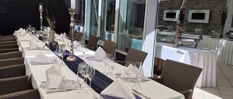 Un restaurante con terraza, cubierto por un toldo grande, y mesas dispuestas con manteles blancos y cubiertos.