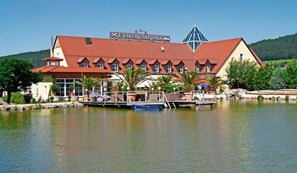 Un hotel de techo rojo, un cartel que dice 'Fichtelgebirgs' y un muelle con un bote.