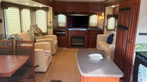 Interior compacto de una caravana con kitchenette, zona de estar y televisor.