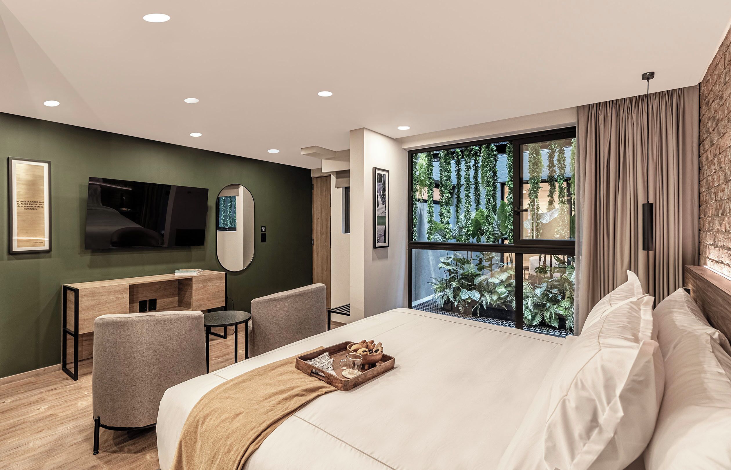 Une chambre d’hôtel moderne, dotée d’un grand lit, d’un bureau, d’une chaise, d’une télévision et d’une fenêtre donnant sur un paysage verdoyant.