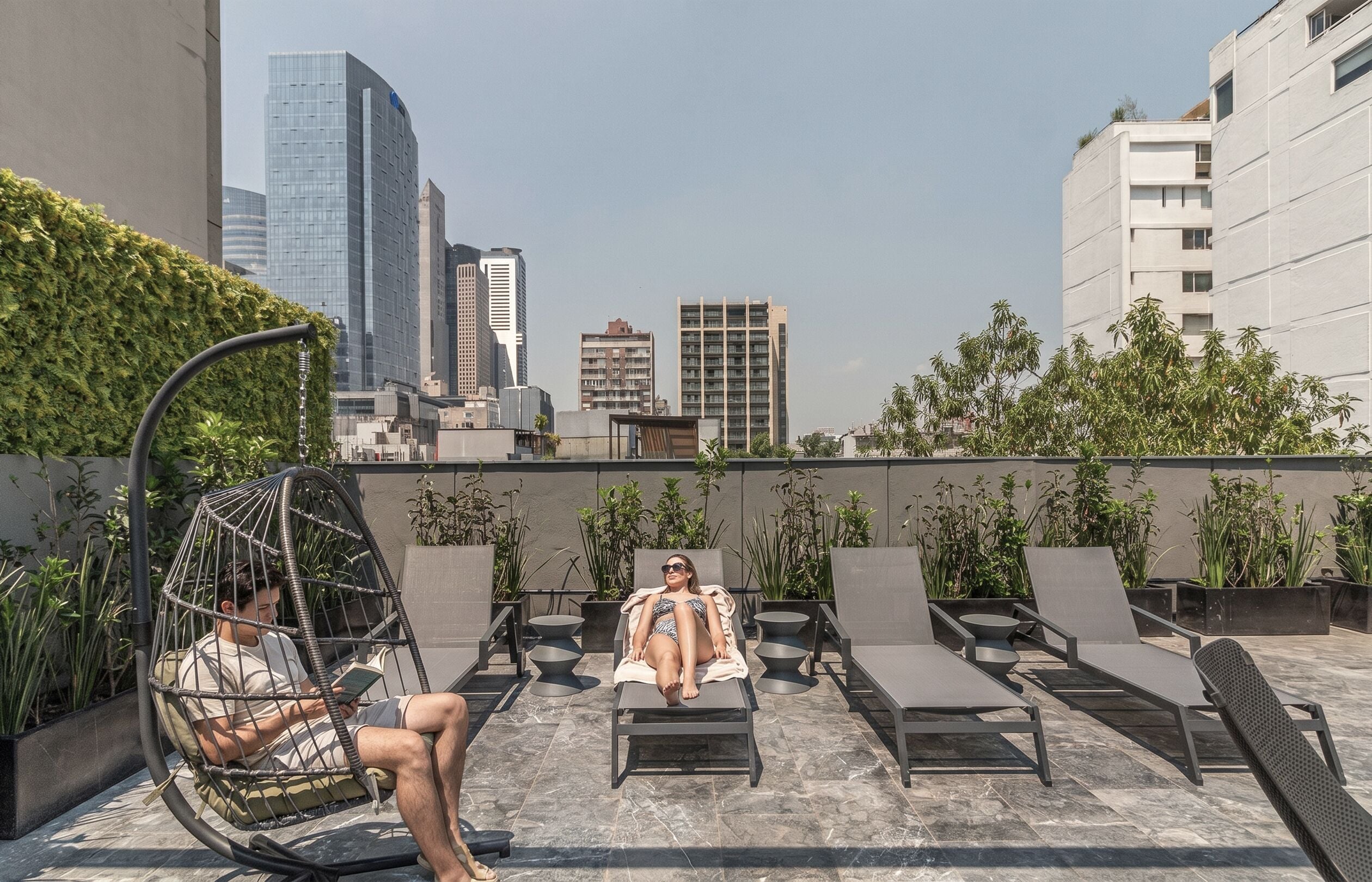 Een dakterras met loungestoelen, een hangstoel en plantenpotten.