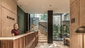 A reception area with a wooden counter, a staircase with marble steps, and a view of outdoor seating.