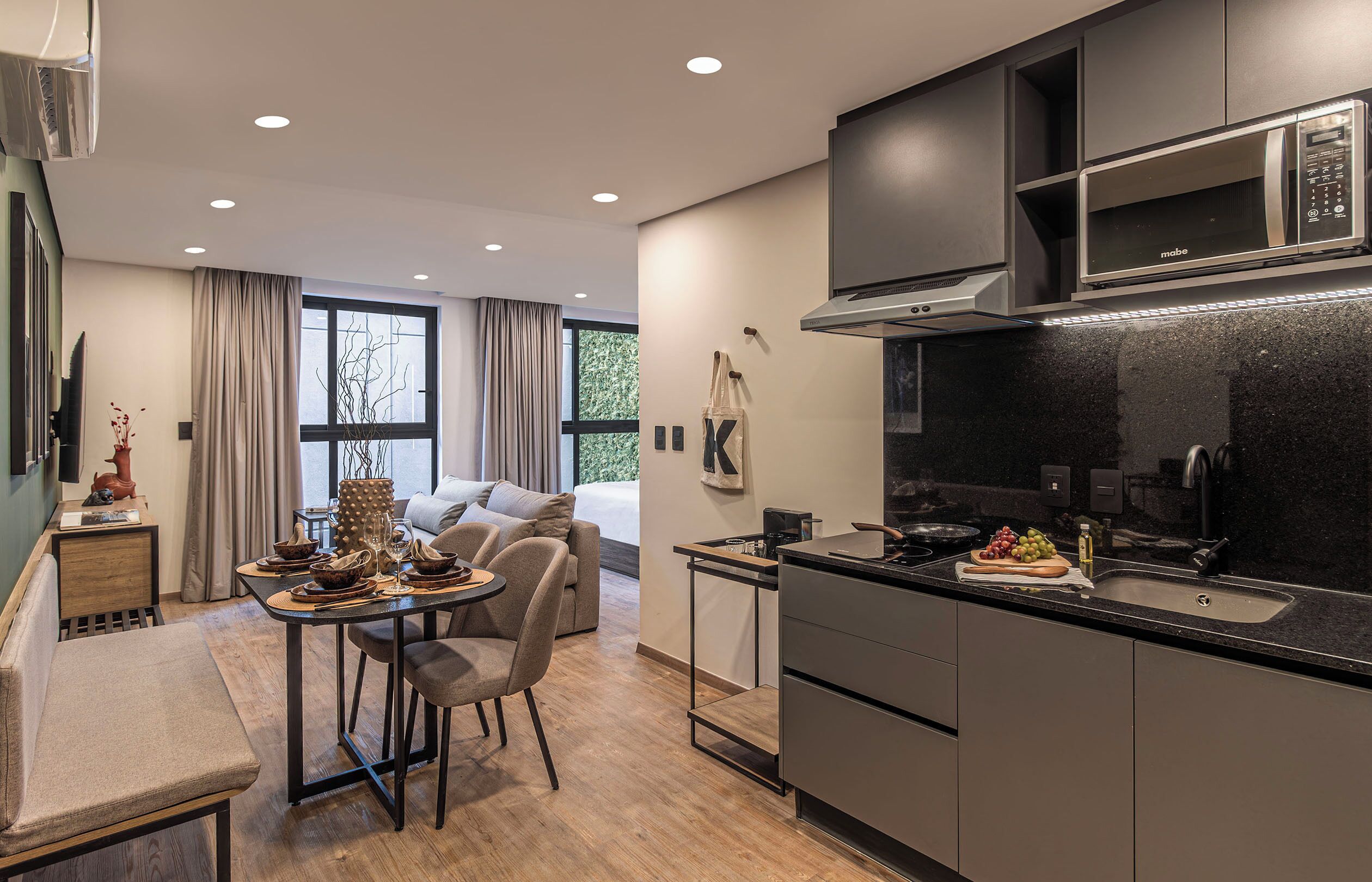 A modern kitchen with a built-in microwave, a dining area with a table and chairs, and a large window providing natural light.