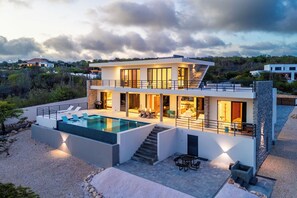 A modern two-story house with a swimming pool, outdoor seating, and a staircase leading to the upper level. - Villa Marah - Luxury Villa with Rooftop Terrace & Ocean Views (Kralendijk)